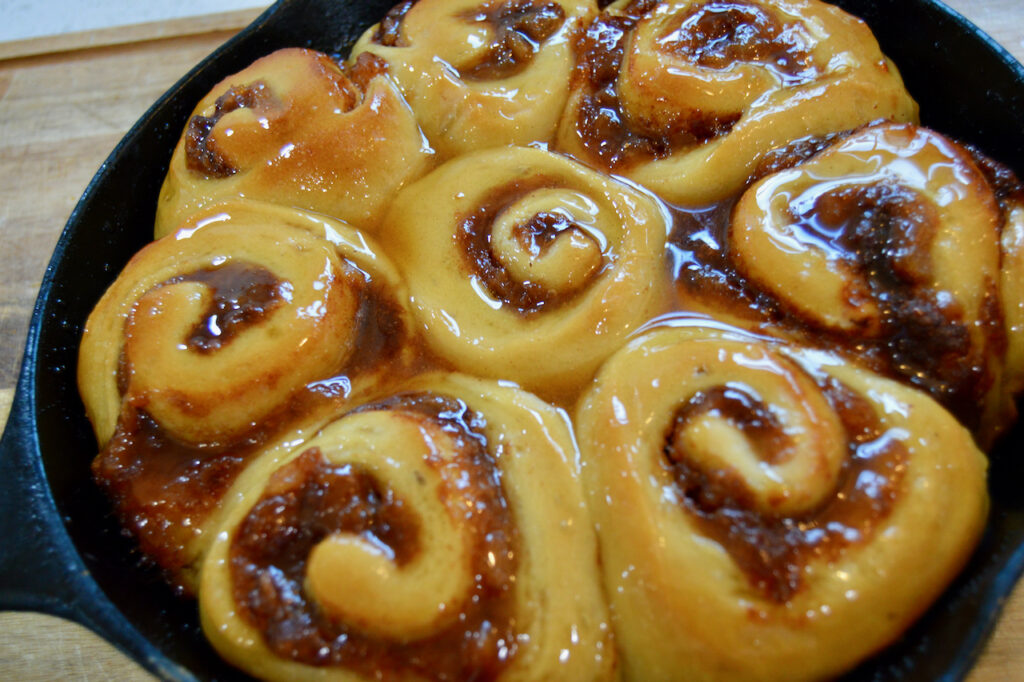 Honey glazed pear butter sourdough cinnamon rolls baked in a cast iron pan.