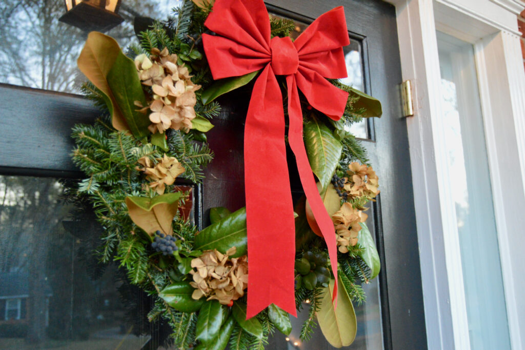 DIY Christmas wreath displayed on a front door with a cheerful bow.