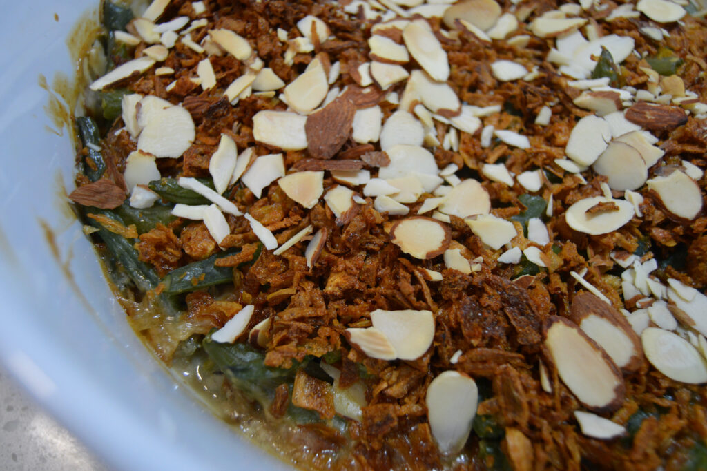 Fresh green bean casserole topped with toasted sliced almonds and crispy onions.