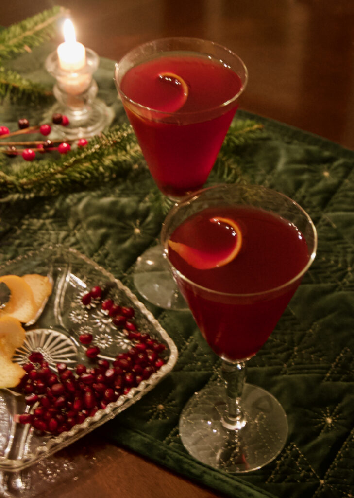 Festive, bright, cheerful pomegranate twist cocktail with an orange peel twist.